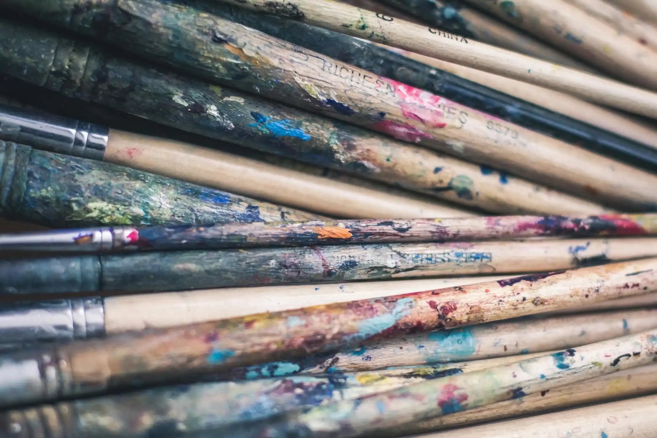 Stack of paintbrushes with paint streaks on handles